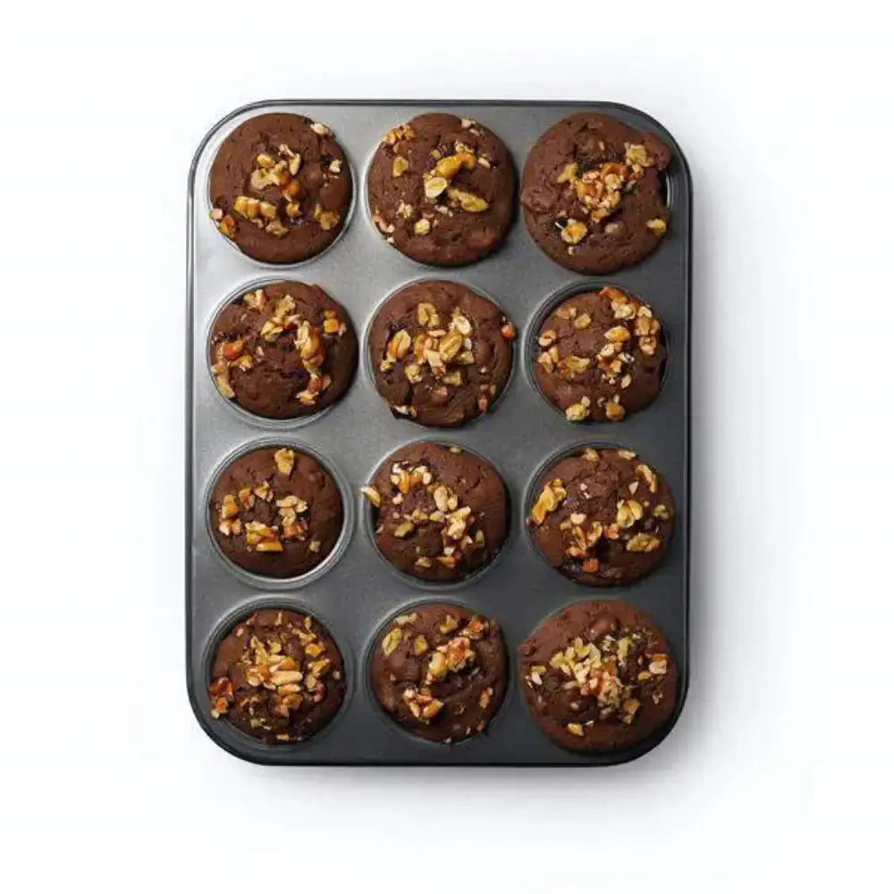 Muffin tray with brown muffins topped with nuts on a white background