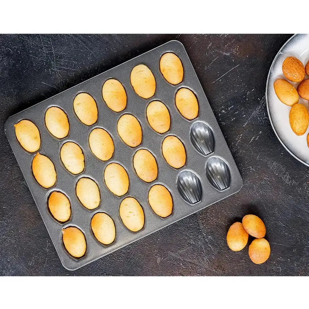 Madeleine cookie mold with baked cookies on a dark surface
