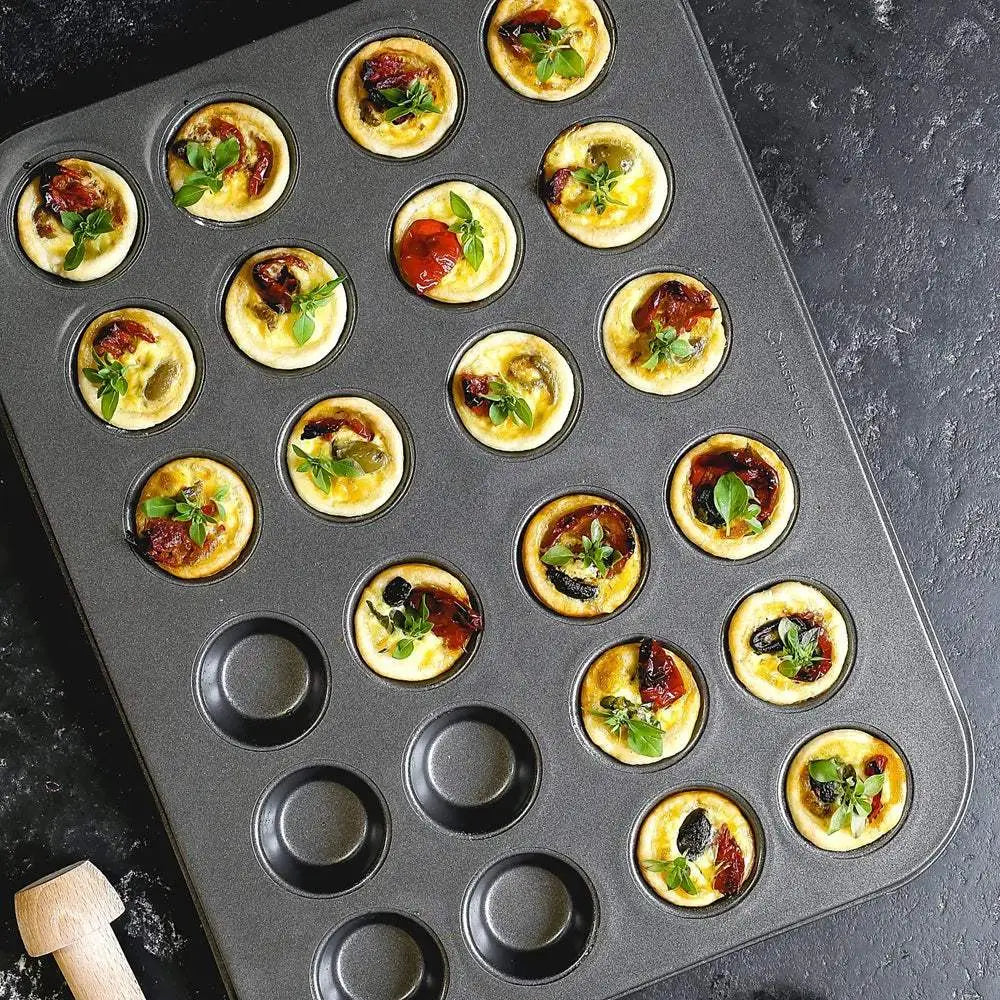Mini quiches in a muffin tin on a dark surface