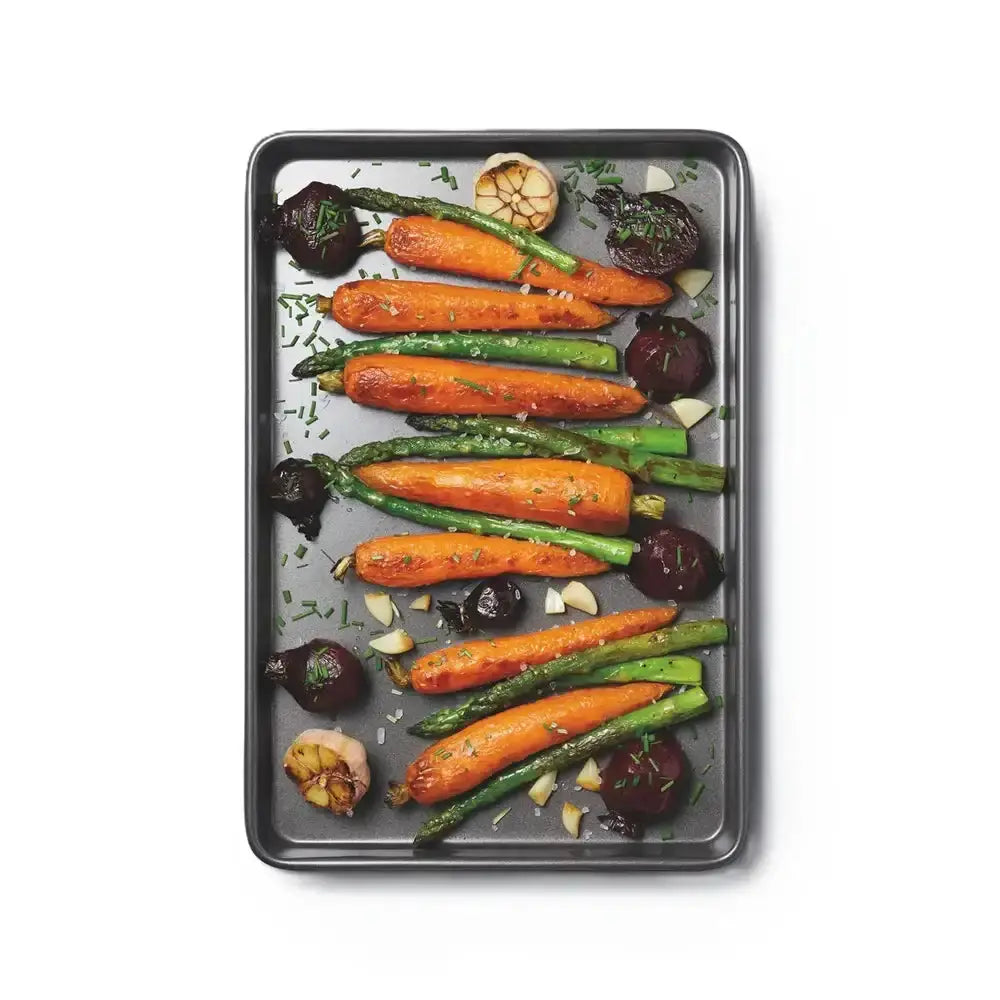 Roasted vegetables including carrots, green beans, and beets on a baking tray.