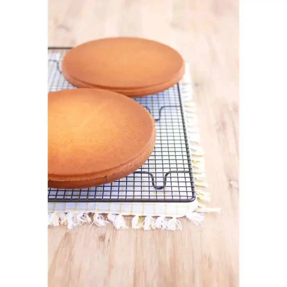 Two round cakes on a cooling rack with a wooden surface underneath