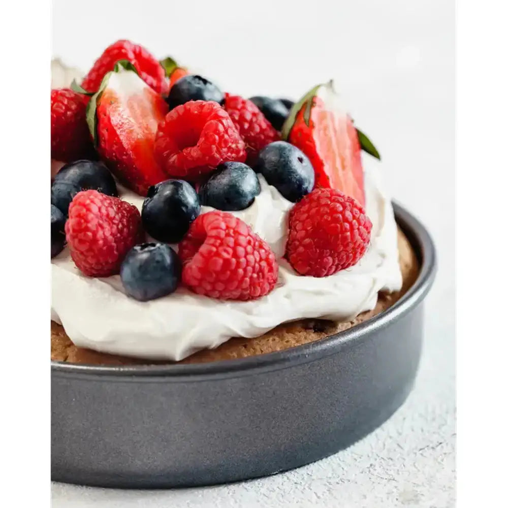 Berry-topped dessert in a round baking pan on a light background