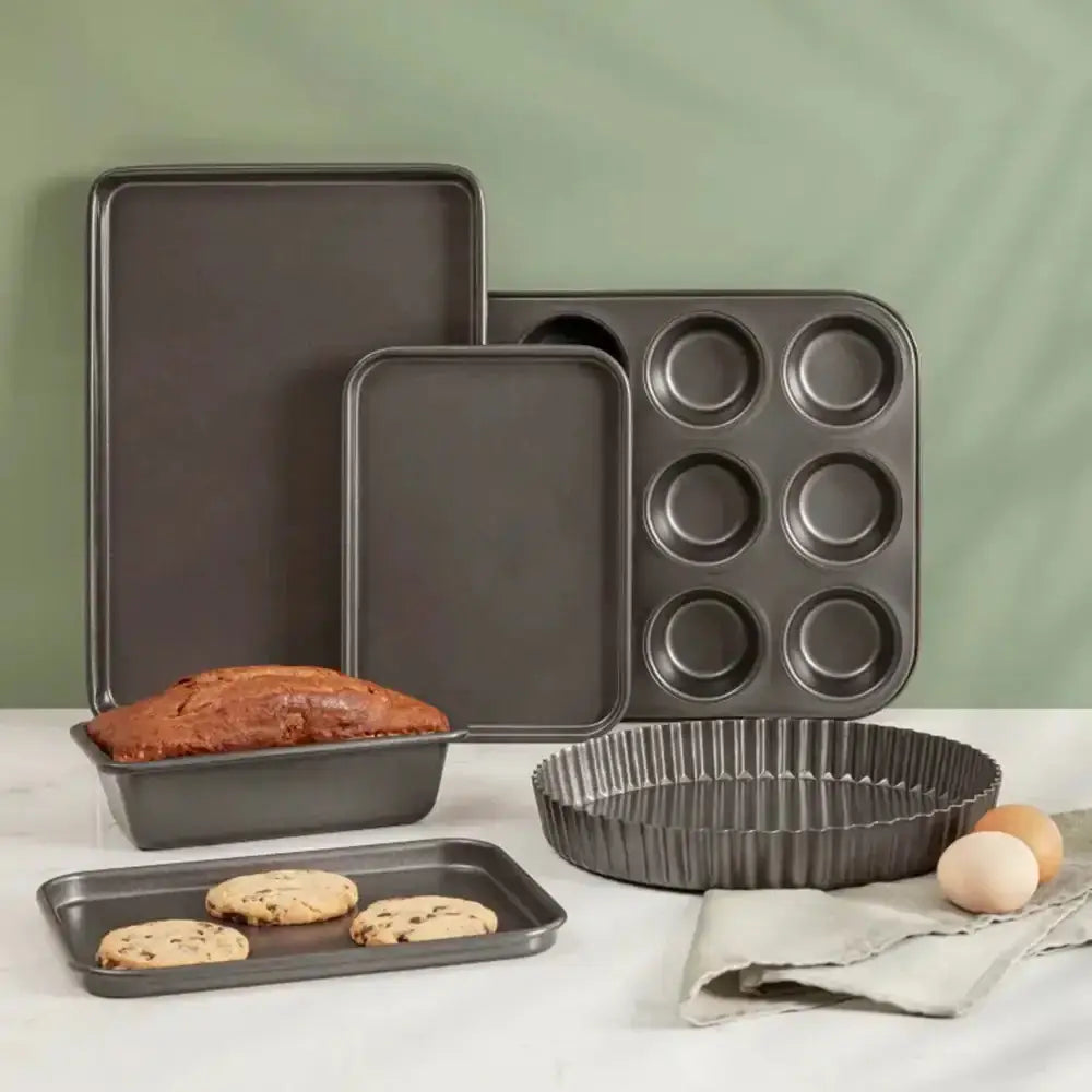 Set of baking pans including loaf, muffin, and tart pans on a white surface with a green background.