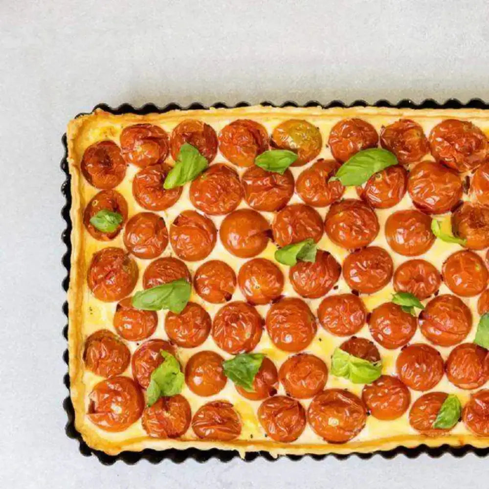 Tomato tart with basil leaves on a light background