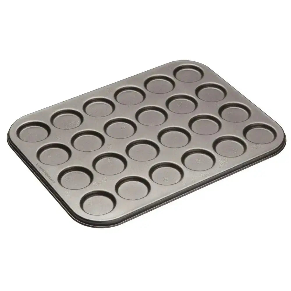 Metal muffin tin with 24 small round cavities on a white background
