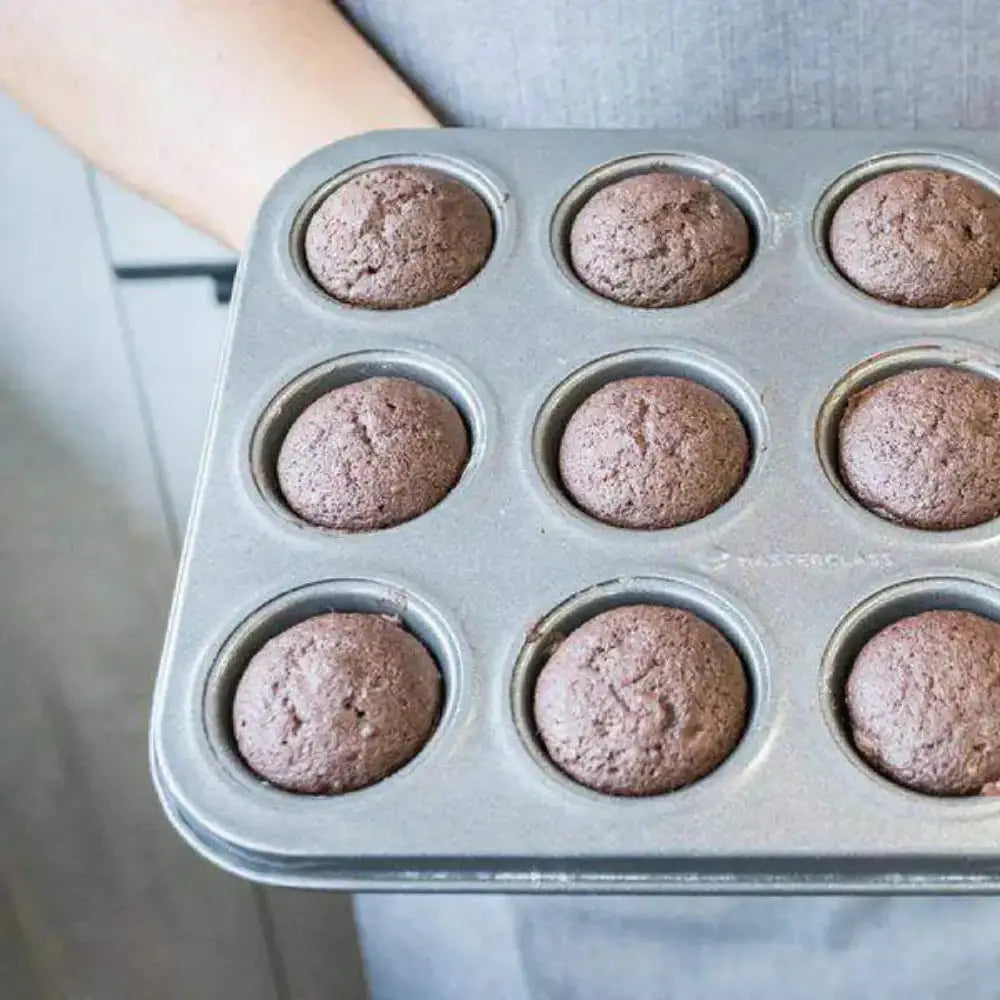 Muffin tin with chocolate cupcakes on a neutral background