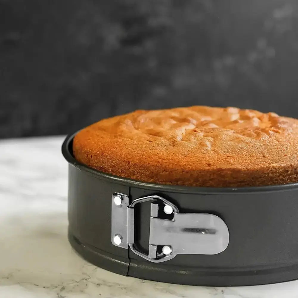 Baked cake in a springform pan on a marble surface with a dark background