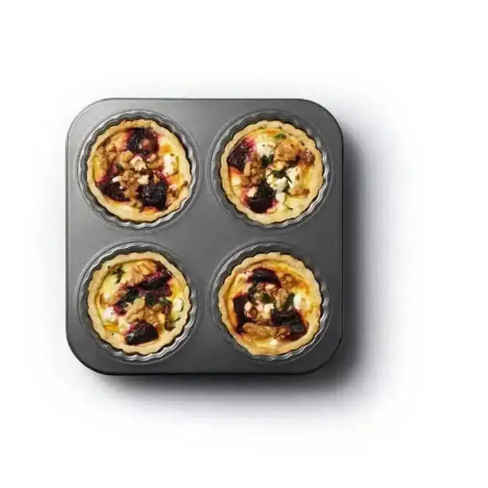 Four mini quiches in a muffin tin on a white background