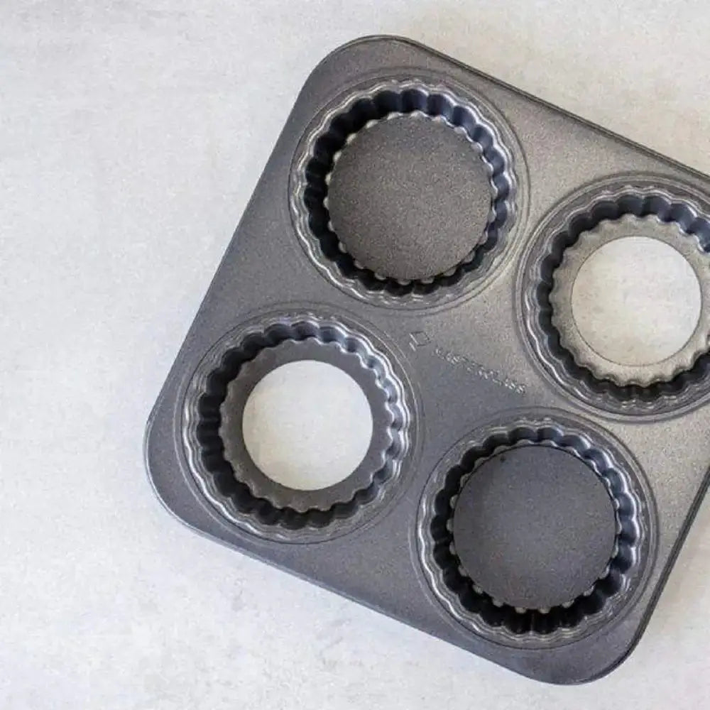 Bundt cake pan with four round cavities on a white surface