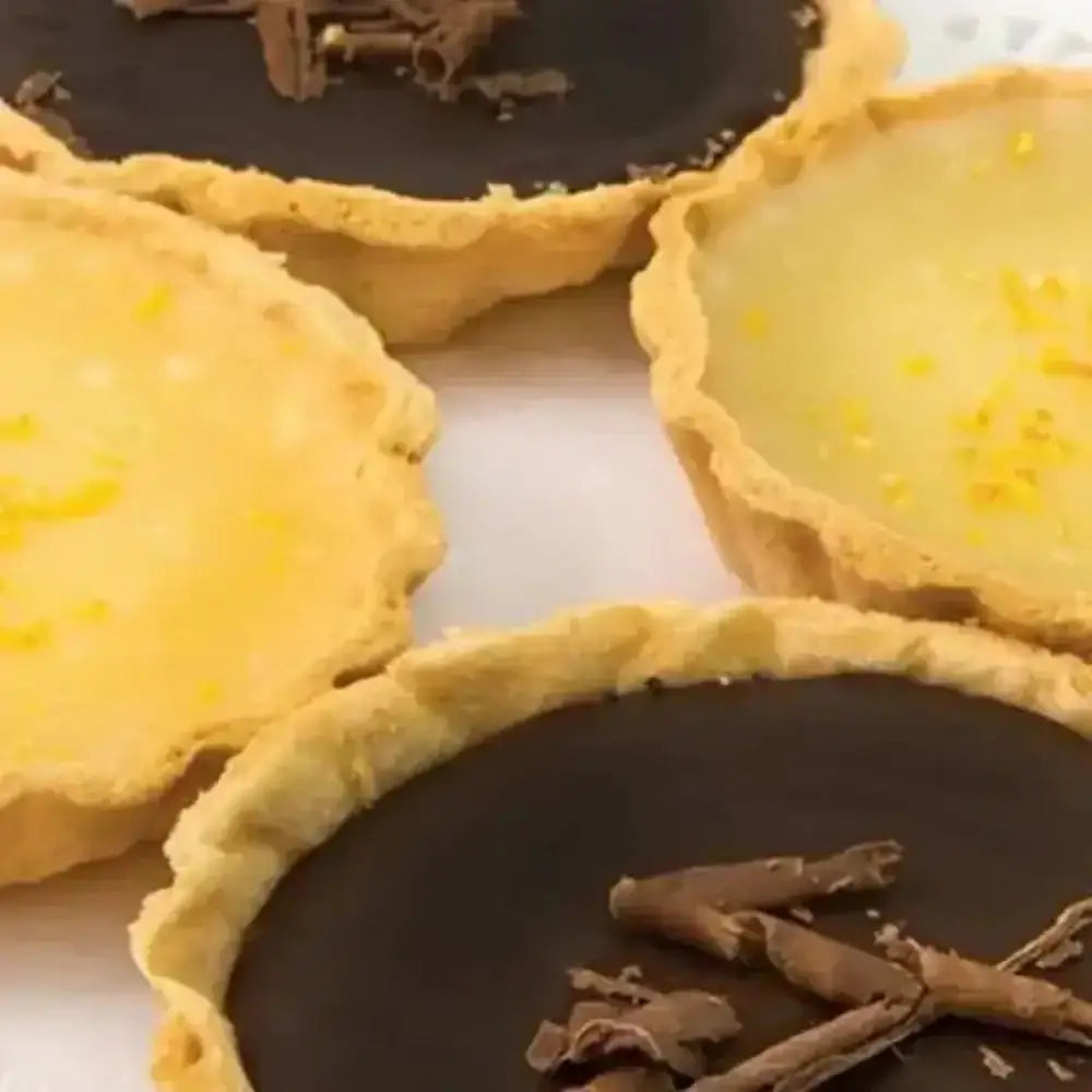 Close-up of chocolate tarts with a yellow filling on a white surface