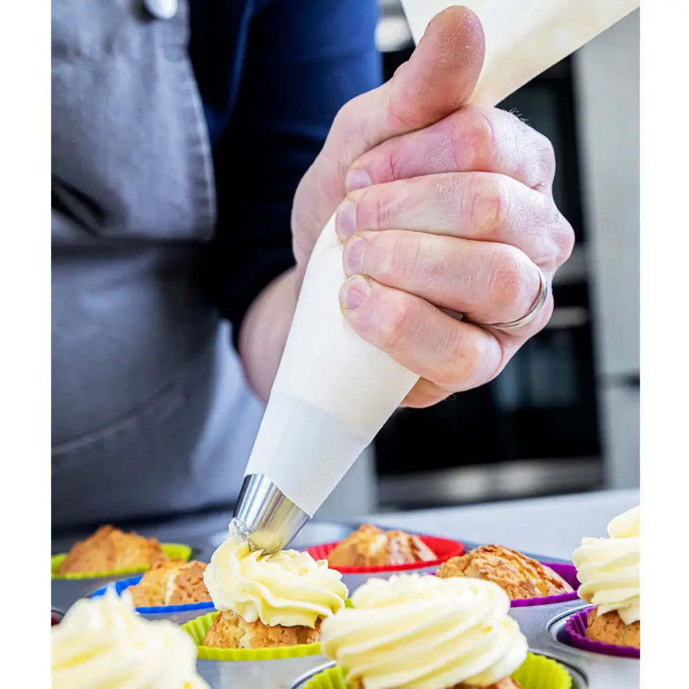 Hand using a piping bag to decorate cupcakes in a kitchen setting