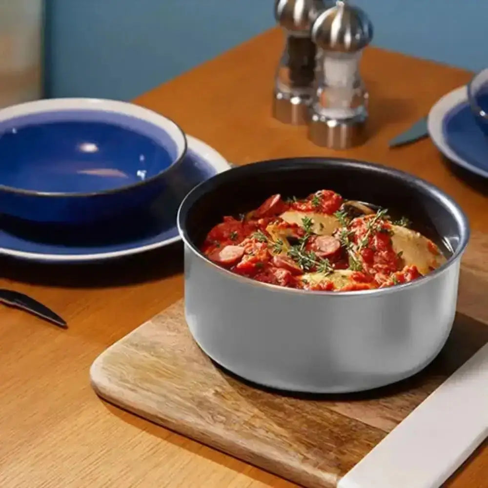 Gray bowl with food on a wooden table with blue plates and salt and pepper shakers.