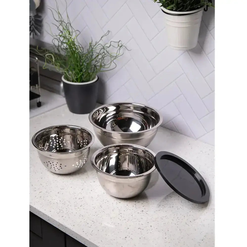 Set of stainless steel mixing bowls with lids on a kitchen counter.