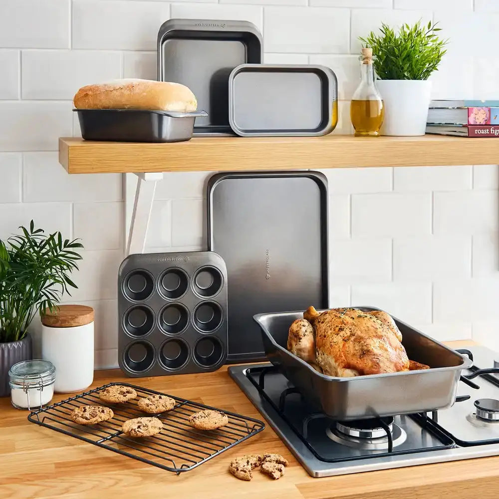 Kitchen scene with baking trays, a roasted chicken, and plants on a wooden shelf.