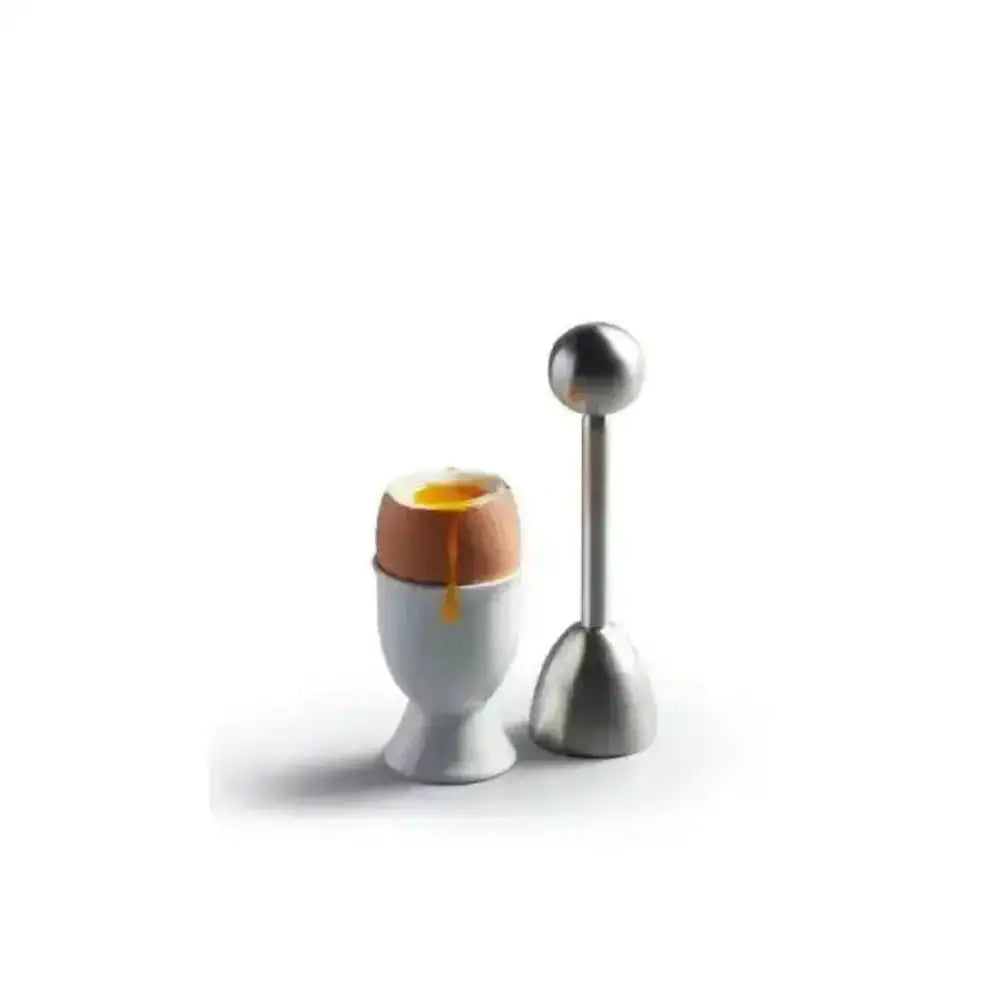 Egg cup with a cracked boiled egg and a metal tool on a white background