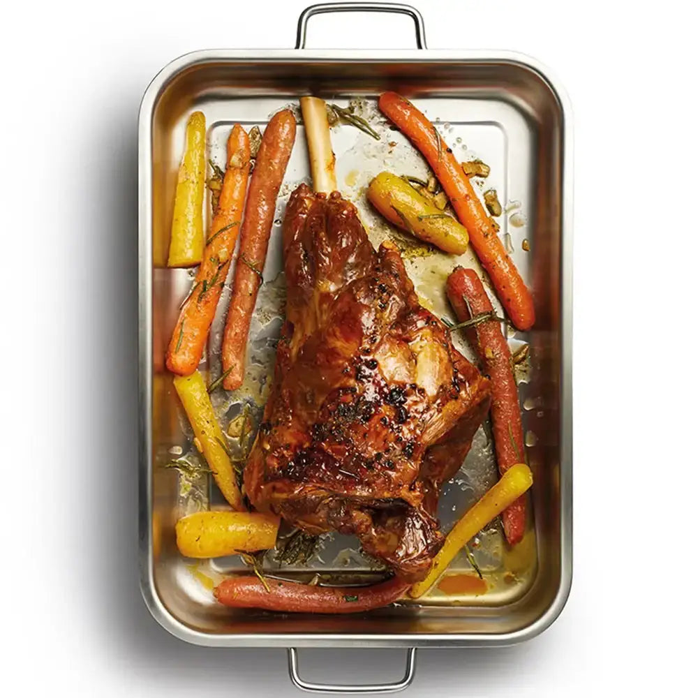 Roasted lamb Shank with carrots and peppers in a roasting pan on a white background