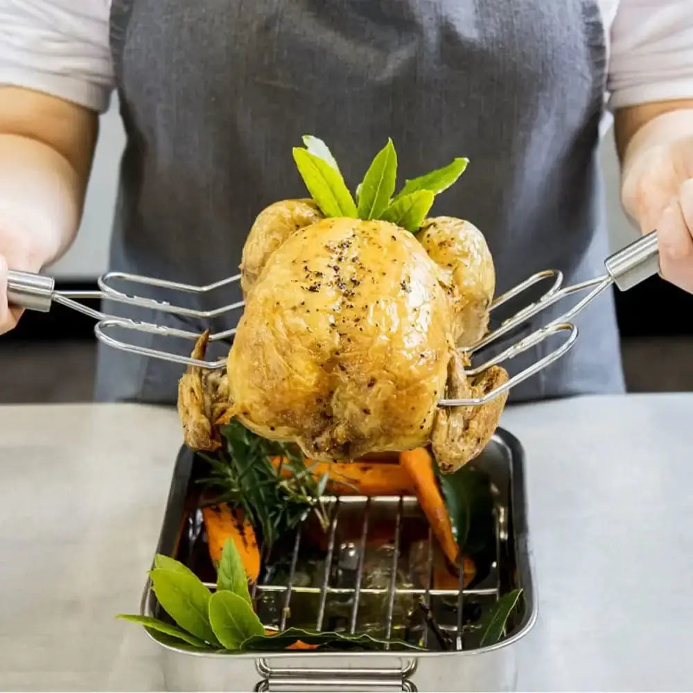 Roasted chicken being held by tongs with herbs on a metal tray