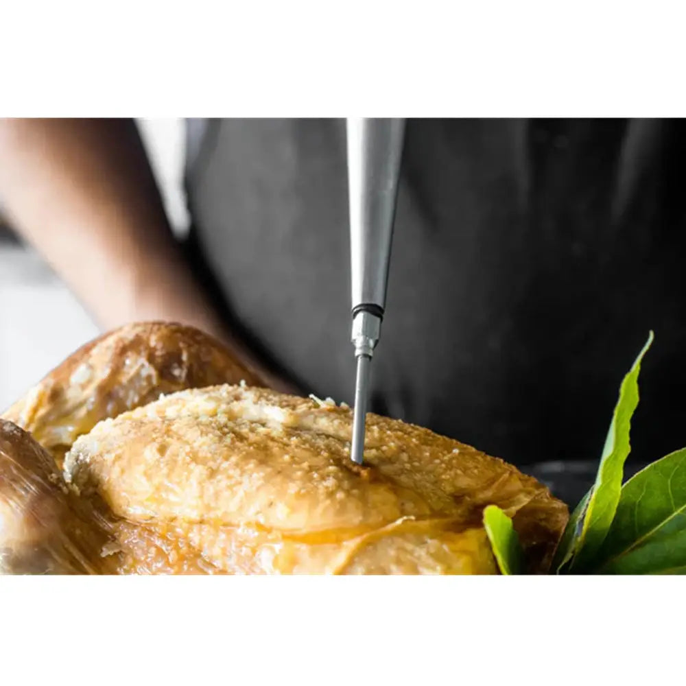 Person using a small knife to cut into a piece of bread with a leaf on a white background