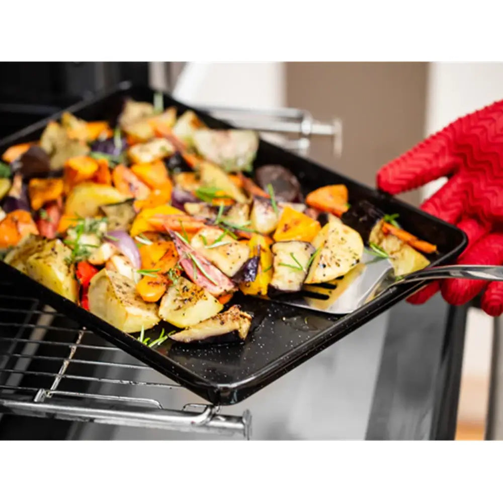 Person holding a tray of roasted vegetables and chicken with a red oven mitt.