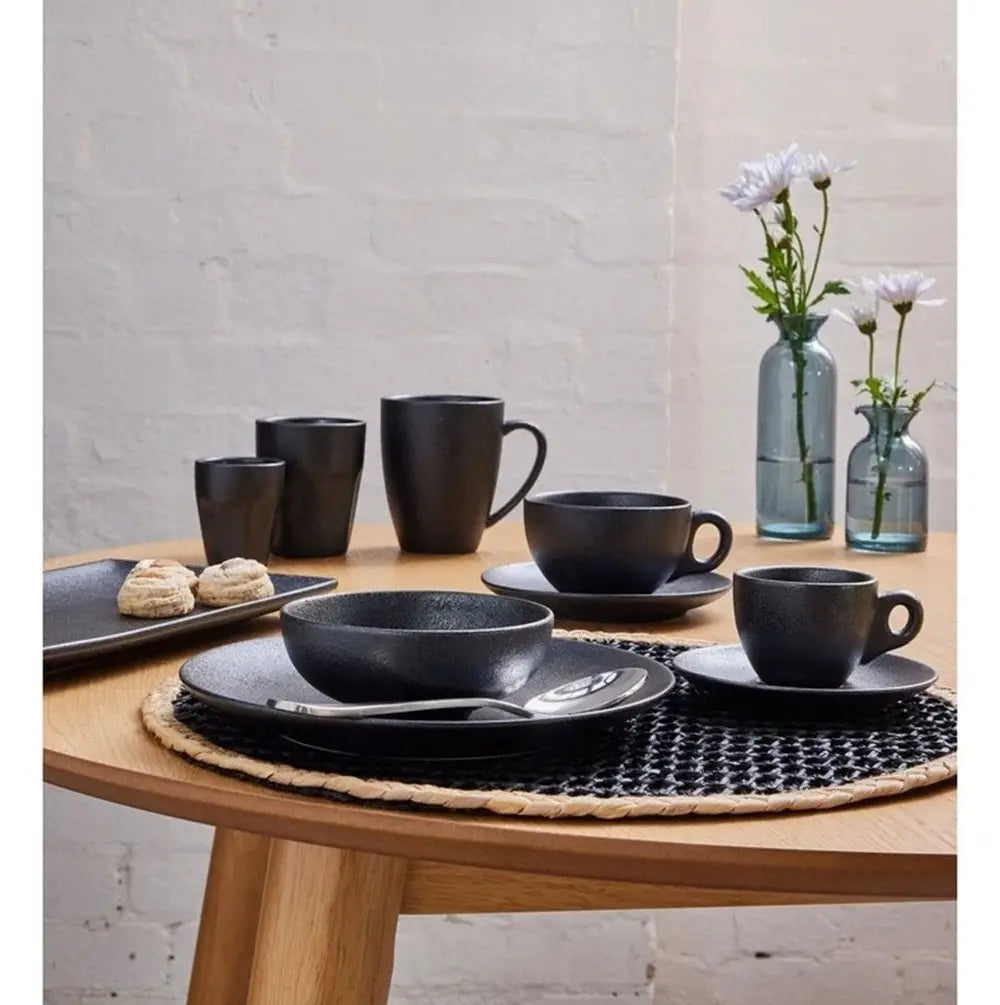 Black ceramic tableware set on a wooden table with a neutral background
