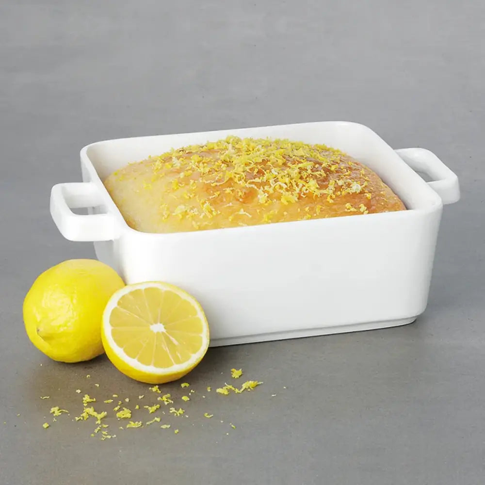 Baked dish in a white rectangular baking dish with lemons on a gray background
