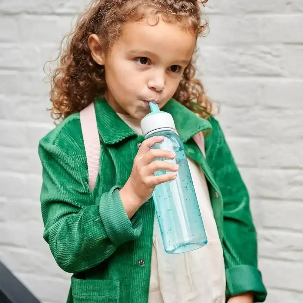 Child in a green jacket drinking from a blue water bottle with a straw.