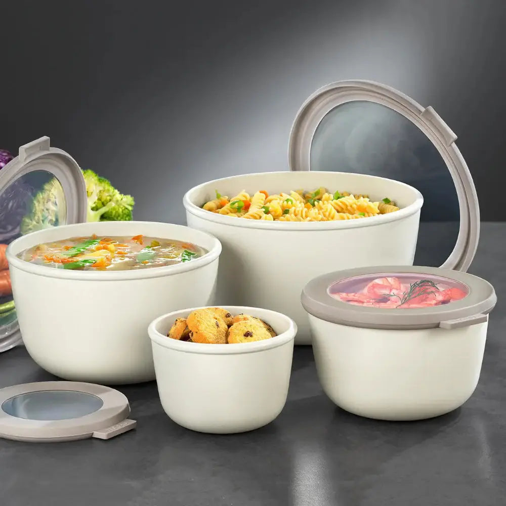 Set of white food containers with various foods inside on a dark background