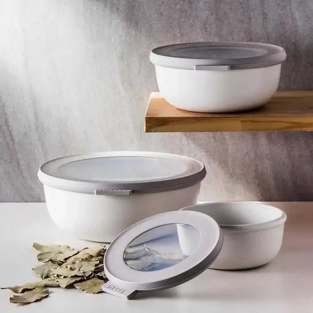 Set of three white food storage bowls with grey lids on kitchen counter and shelf