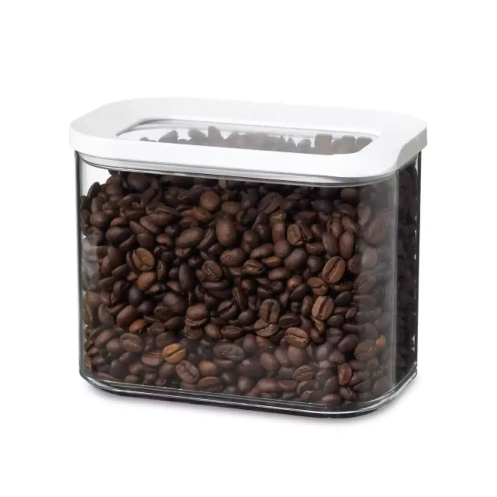 Clear container filled with coffee beans on a white background