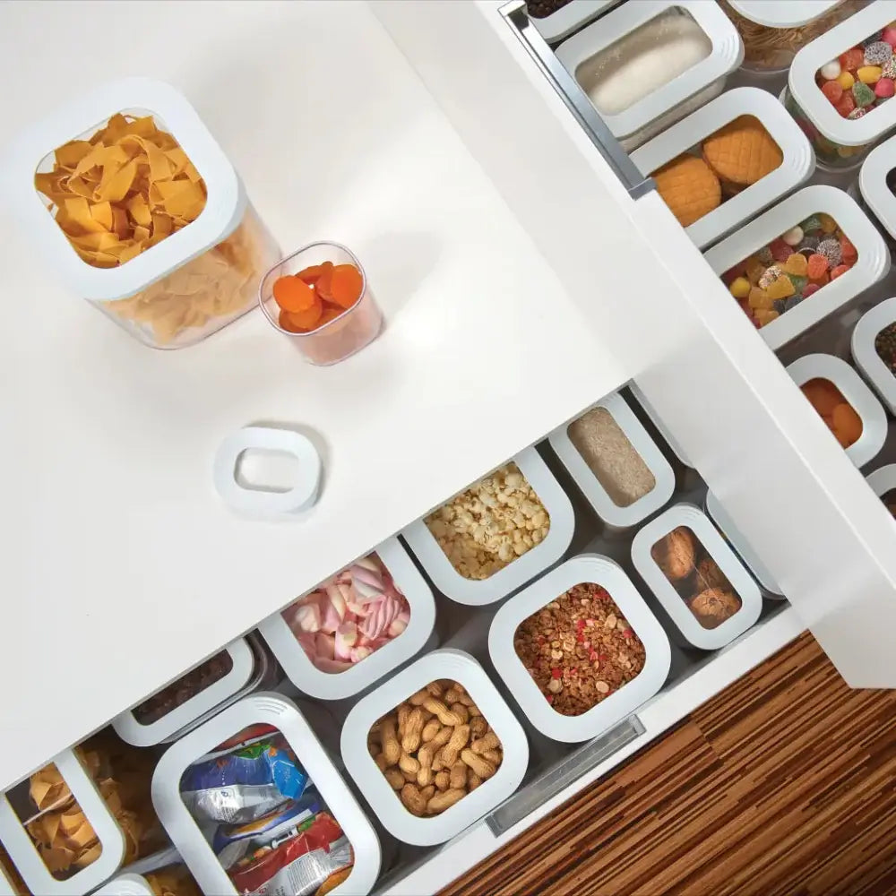 Assorted snacks in small containers on a white surface