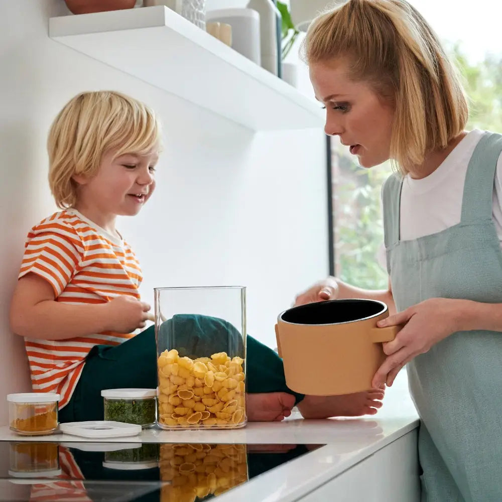 Woman and child in a kitchen preparing food together next to food organising items