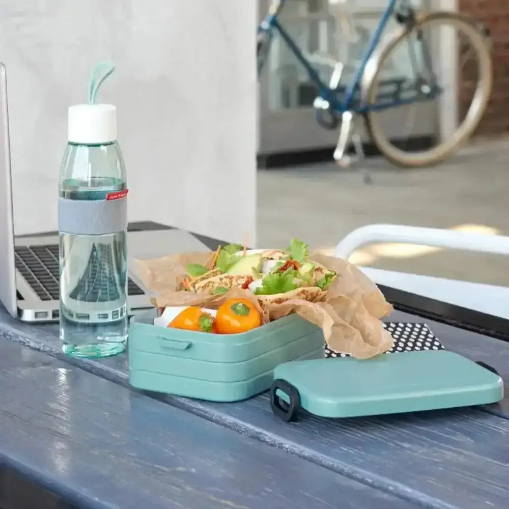 Nordic blue lunch box with fresh food beside a water bottle on an outdoor table
