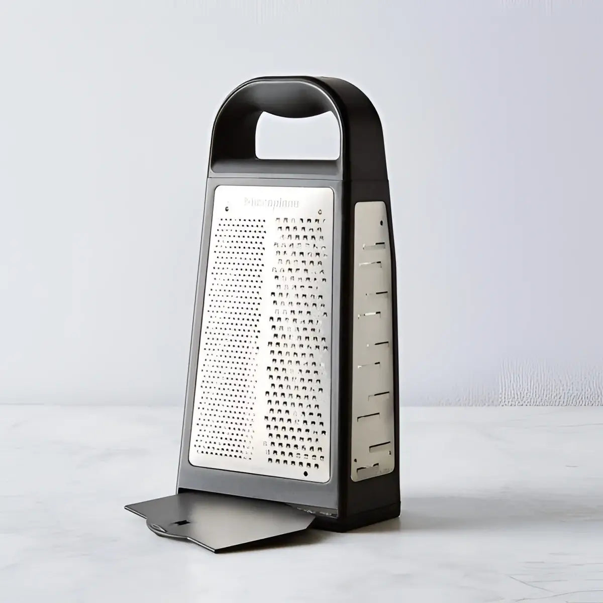 Box grater with black handle and body on a light gray background
