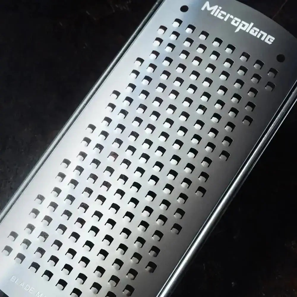 Metal grater with 'Microplane' branding on a dark background