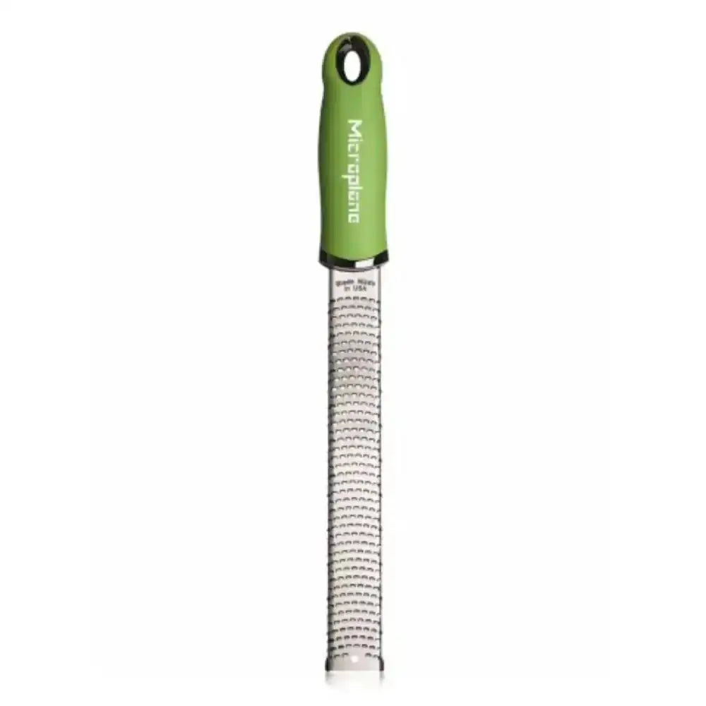 Green handheld grater with metal surface on a white background