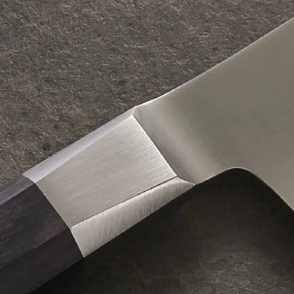 Close-up of a knife blade on a dark textured surface
