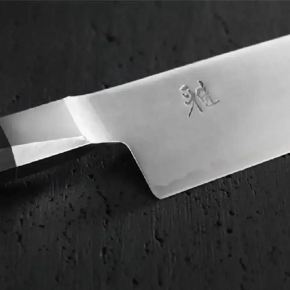 Close-up of a chef's knife blade with a brand logo on a dark background