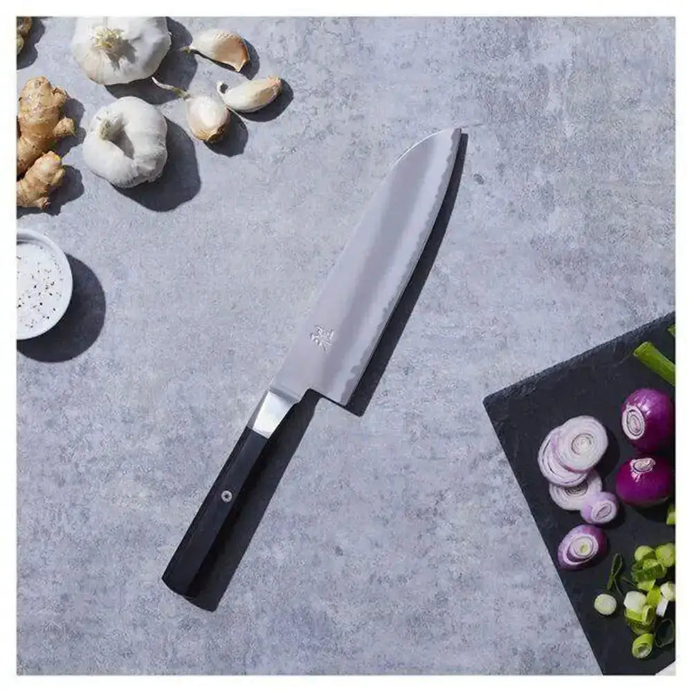 Chef's knife on a gray surface with vegetables