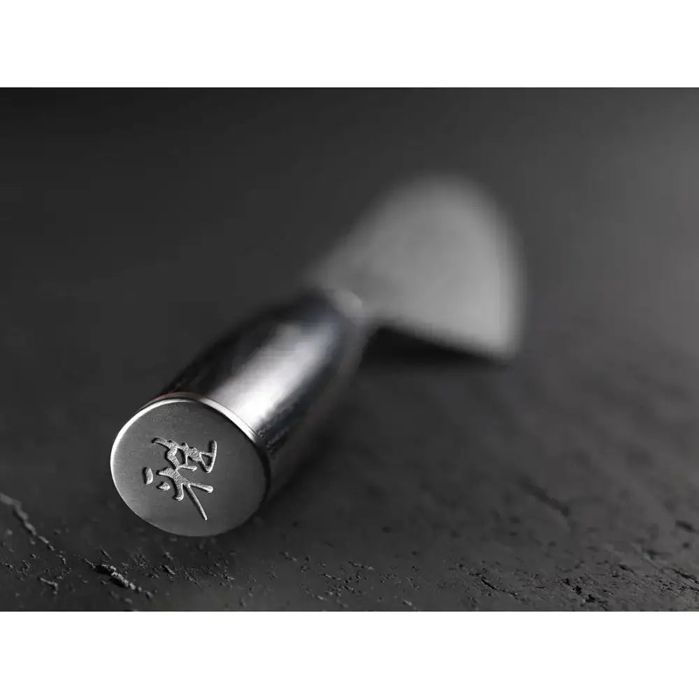 Metallic knife with a textured handle on a dark surface