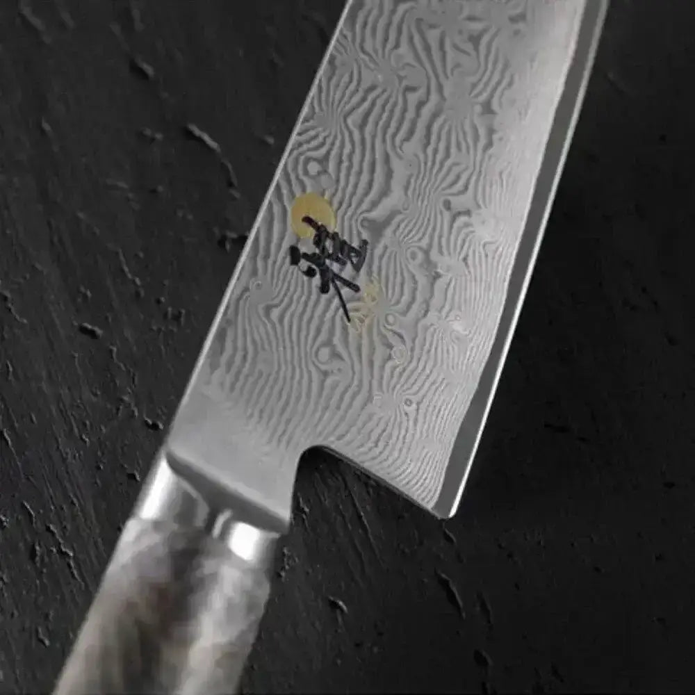 Close-up of a Damascus steel kitchen knife on a dark surface