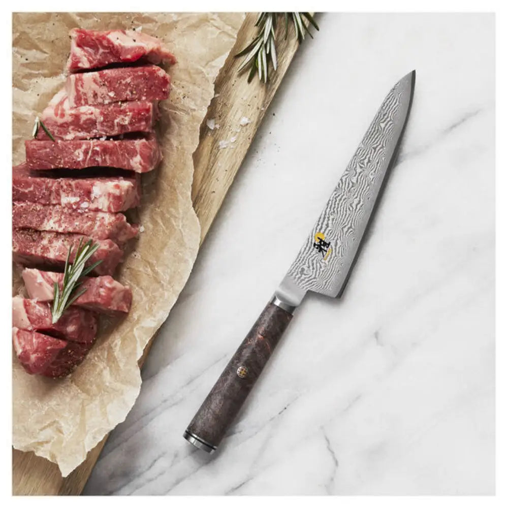 Sliced raw meat on a wooden board with a Damascus knife on a marble surface