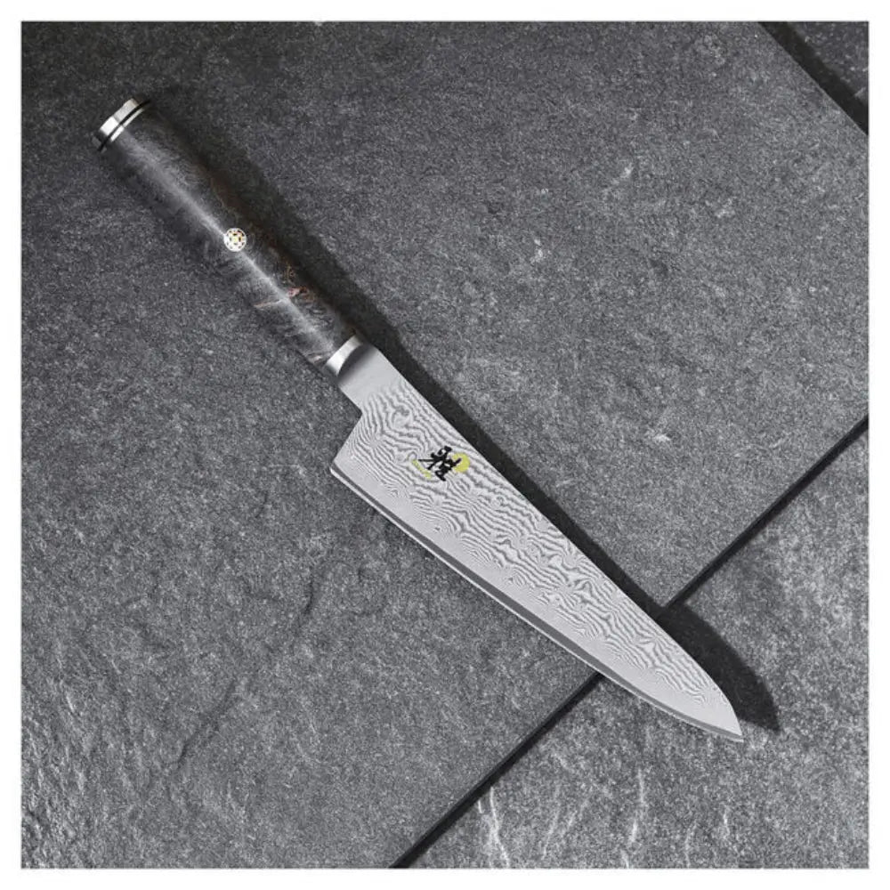 Chef's knife with a black handle on a gray surface