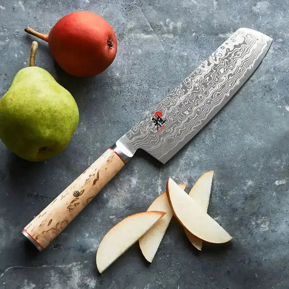 Chef's knife with a decorative blade pattern on a gray surface with sliced pears.