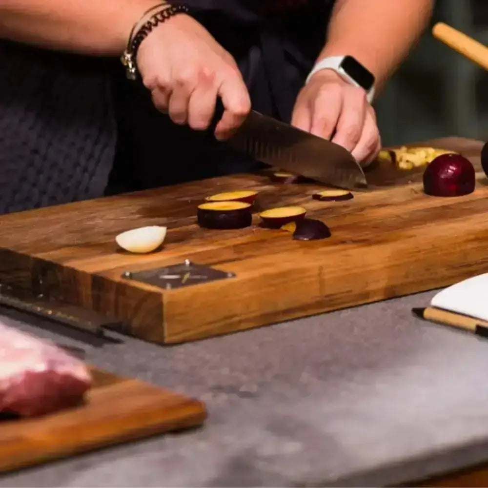 Person cutting food on a wooden cutting board with a knife.