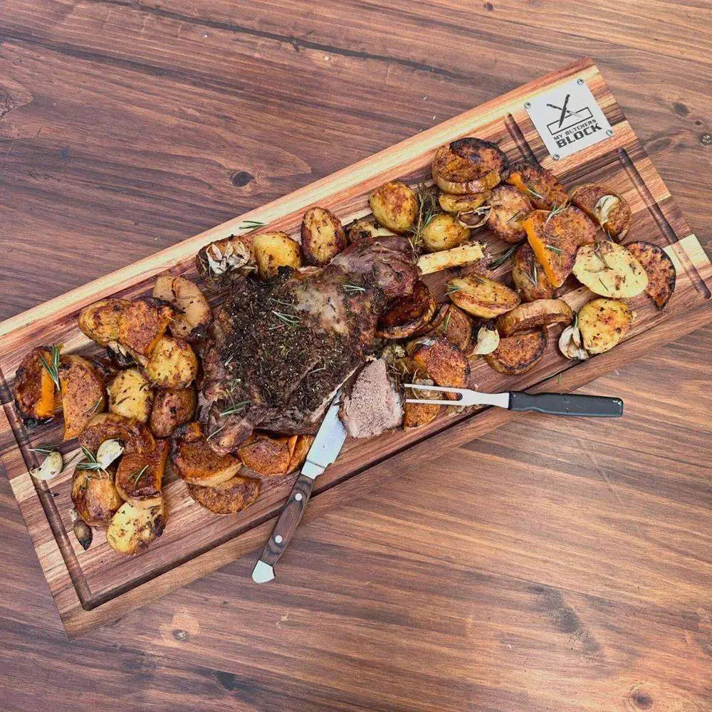 Wooden cutting board with roasted vegetables and a steak on a wooden surface, featuring the 'Y Block' brand.
