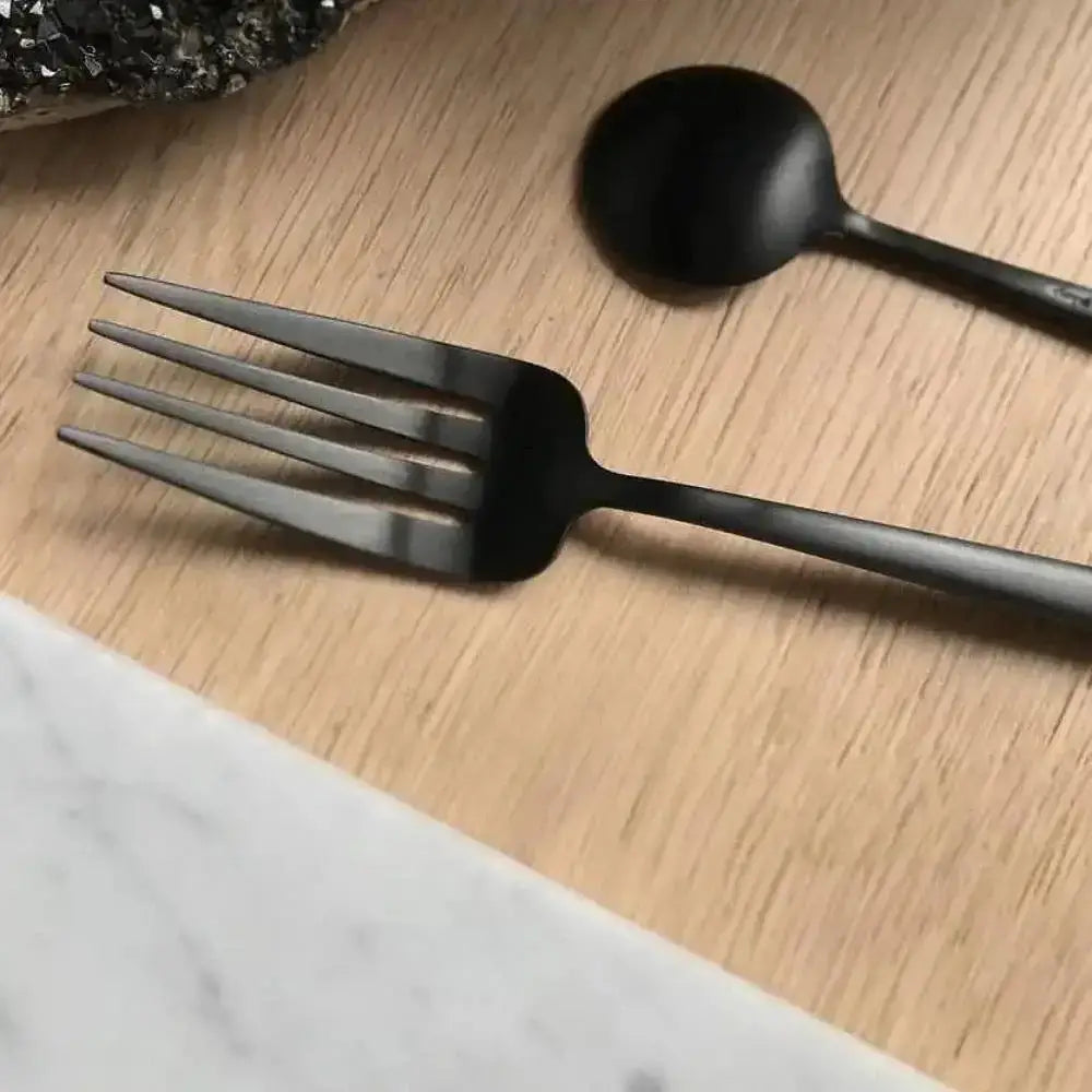 Black fork and spoon on a wooden surface