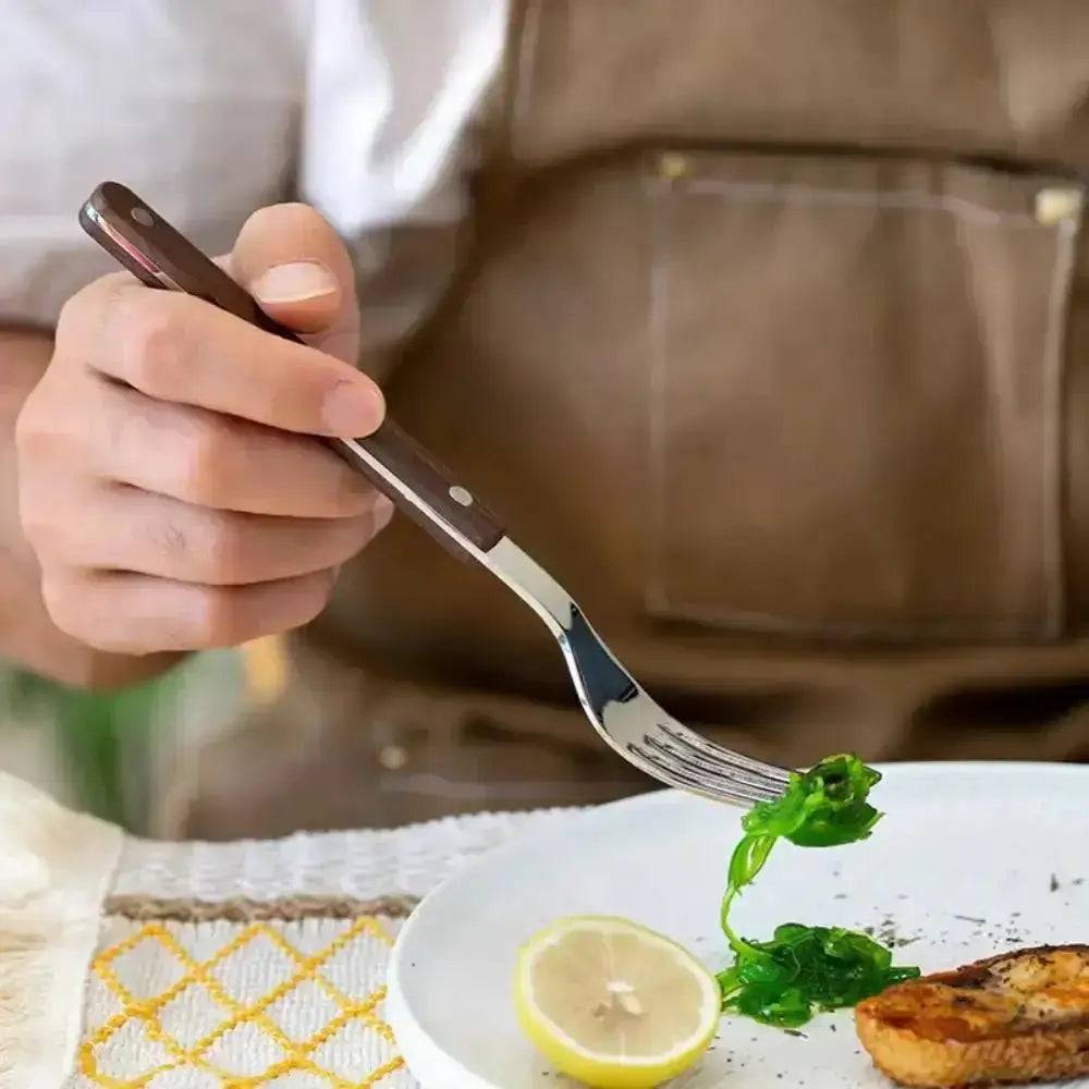 Person holding a fork over a plate with food and a lemon wedge.
