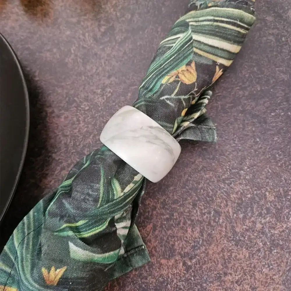 Tropical leaf patterned napkin with a marble effect holder on a dark surface