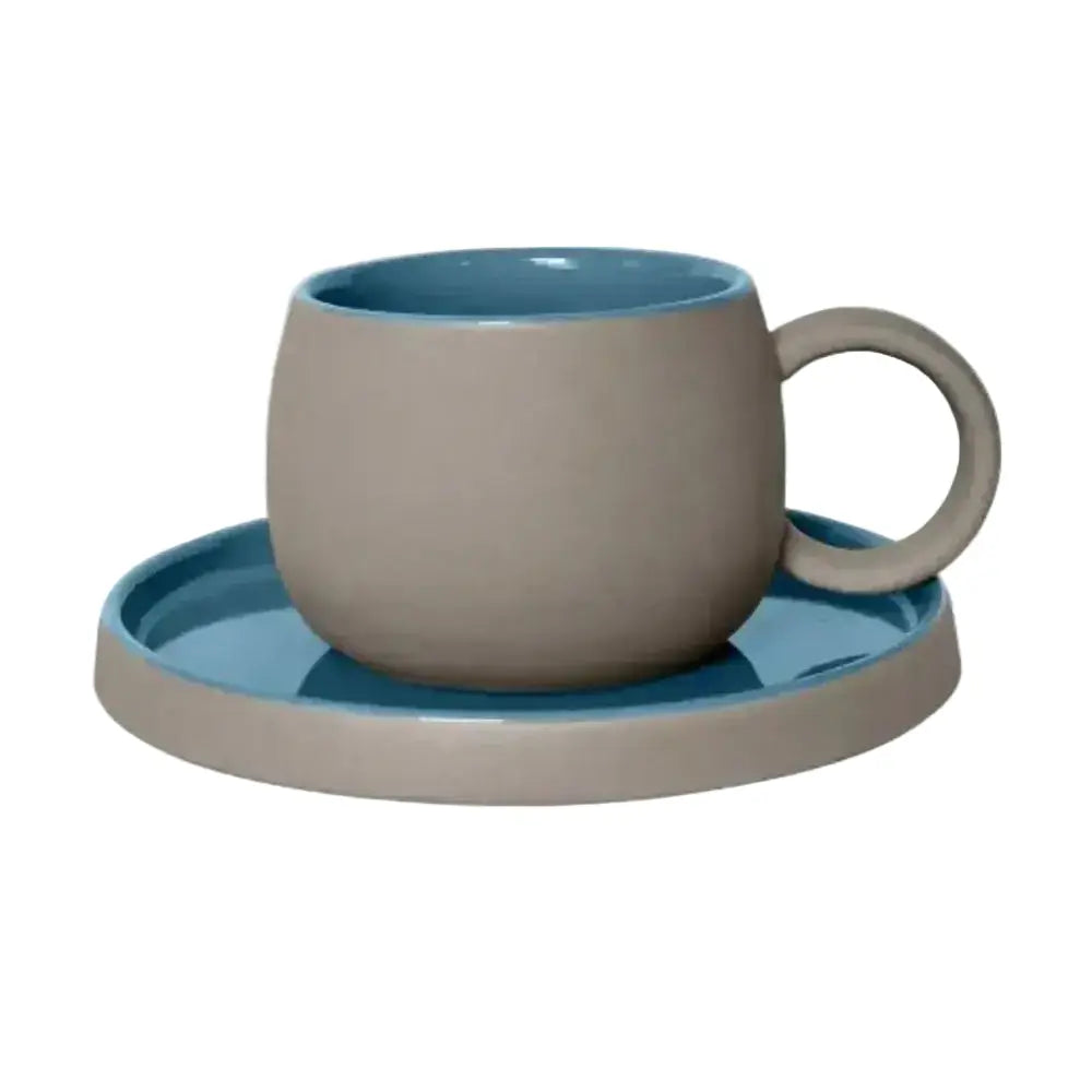 Ceramic cup and saucer set with blue interior and beige exterior on a white background