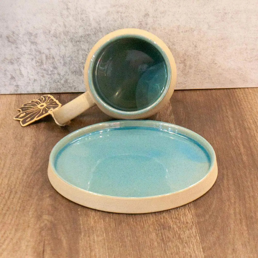 Ceramic mug and plate set with blue interior on a wooden surface